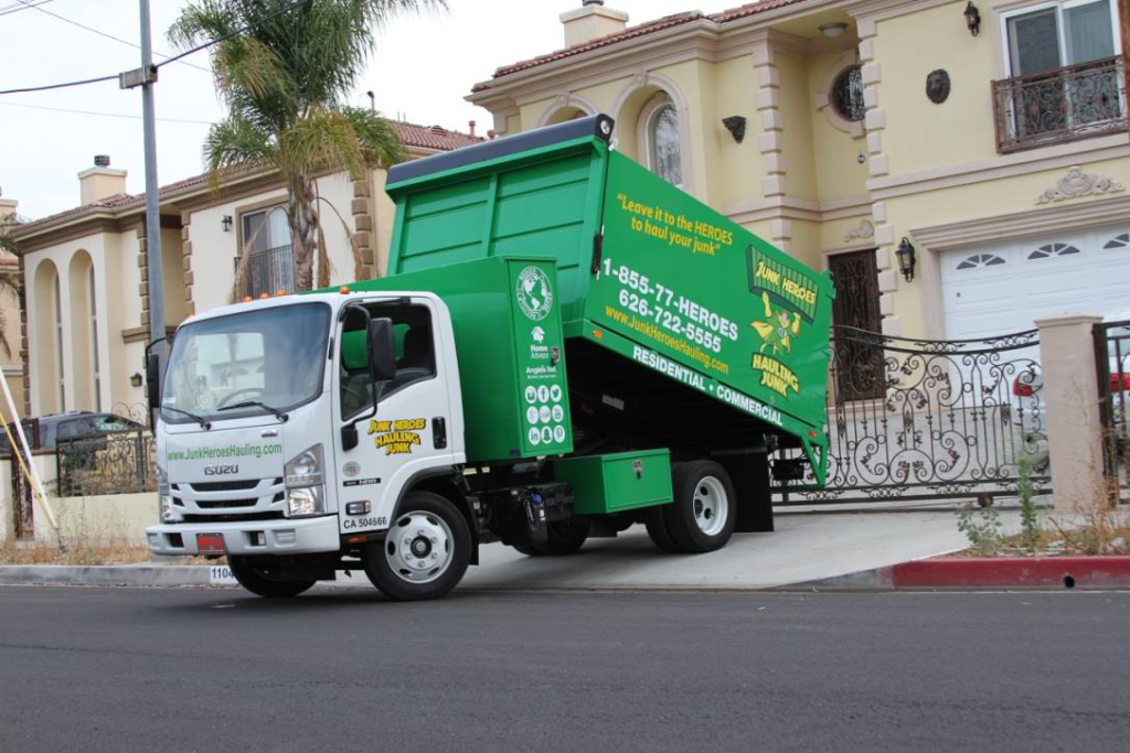 A green and white Junk Heroes Hauling Junk truck parked at a residential property for junk removal service in Pasadena, CA.