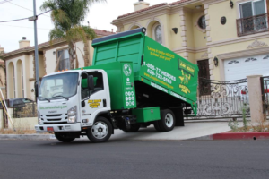A green and white Junk Heroes Hauling Junk truck parked at a residential property for junk removal service in Pasadena, CA.