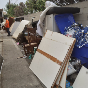 A long pile of household junk, including furniture and appliances, along a wall for Vic's Haul Away & Junk Removal in Garden Grove, CA.