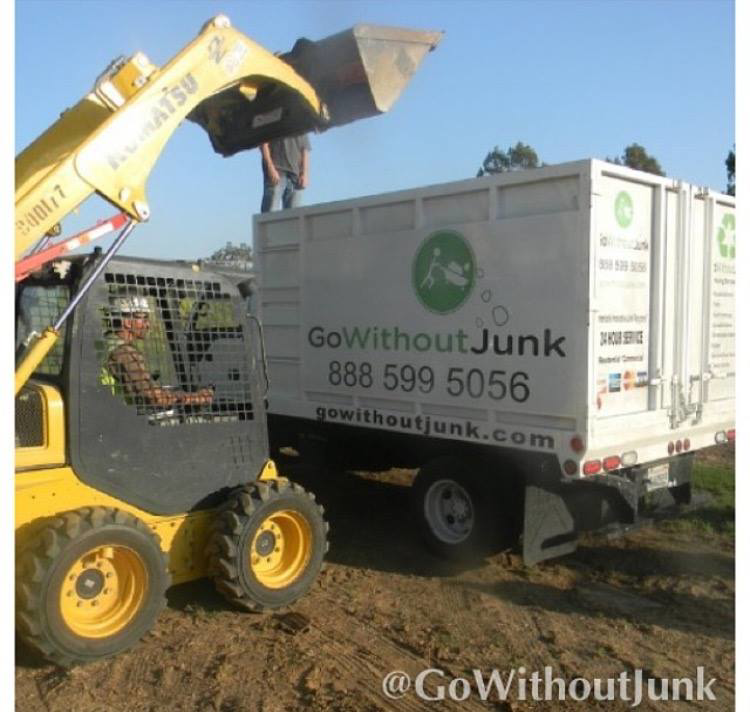 A skid-steer loader filling a GO WITHOUT JUNK truck with debris during a removal job in Burbank, CA.
