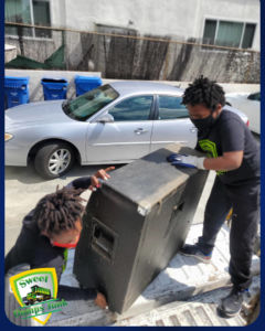Two Sweet Dumps Junk team members carefully loading a large item into a pickup truck in Los Angeles, CA.