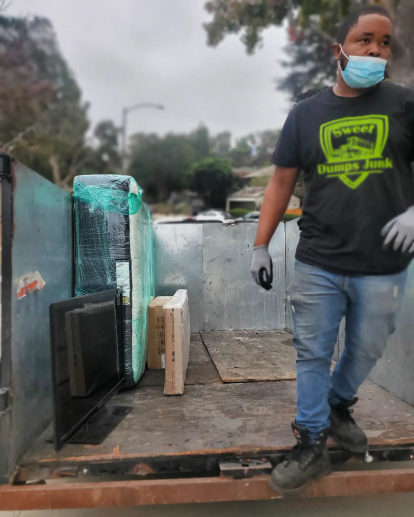A Sweet Dumps Junk team member loads a truck with a mattress and boxes for junk removal in Los Angeles, CA.