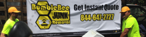 Two workers removing a black item and a white appliance for BumbleBee Junk in Sun Valley, CA.