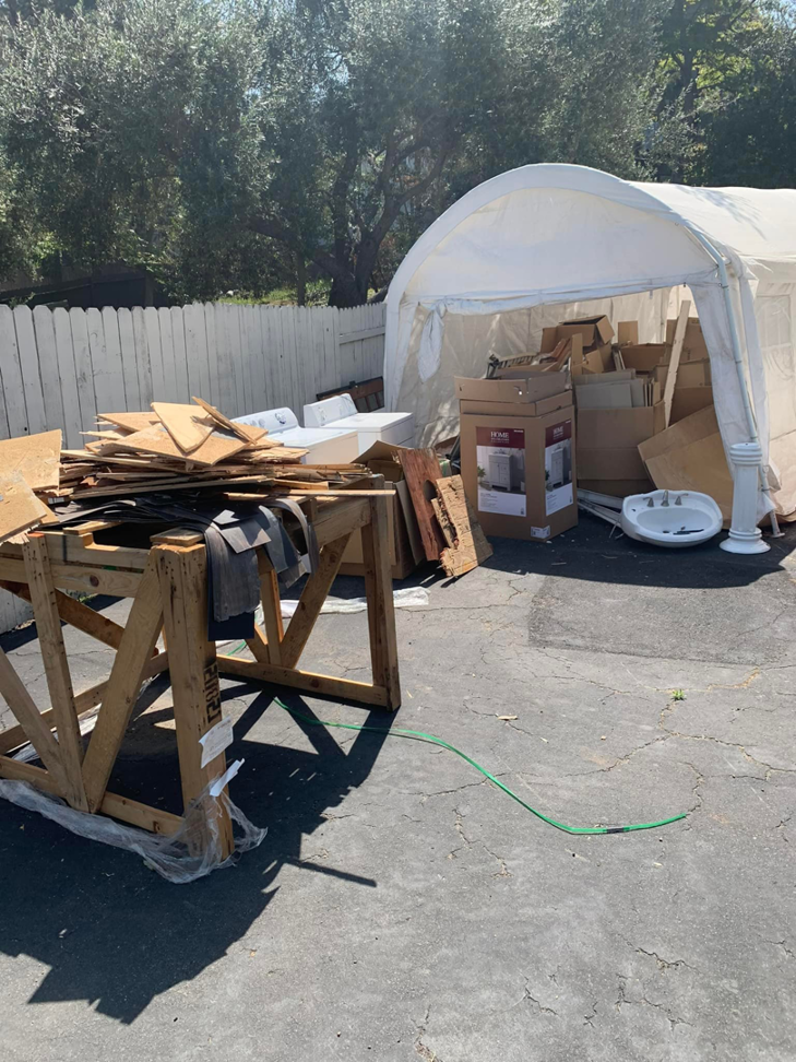 A white canopy tent filled with cardboard boxes, wood scraps, and a sink, awaiting removal by Jake's Junk Removal in San Diego, CA.