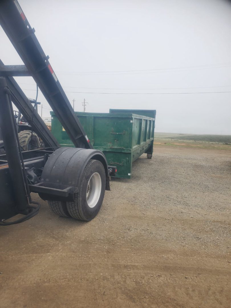 A West Coast Recycle truck delivering a green roll-off dumpster for junk removal in San Jose, CA.