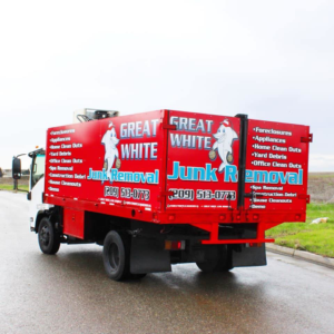 The back of a red Great White Junk Removal truck with its branding driving on a road in Stockton, CA.
