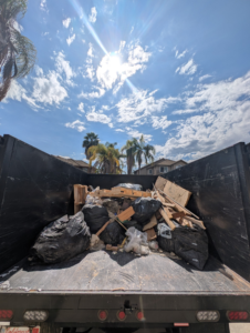 The bed of a Junk Rush truck filled with black trash bags, wooden debris, and other junk after a removal service in San Diego, CA.