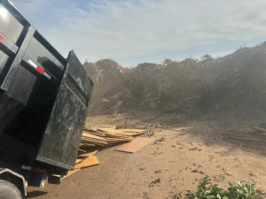 A dump truck from Bakersfield Roll-Off Service at a large-scale debris disposal site in Bakersfield, CA.
