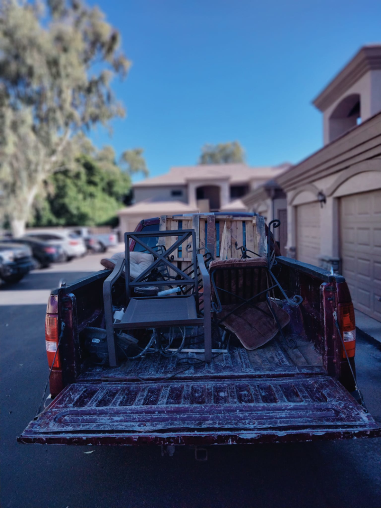 A pickup truck loaded with old outdoor furniture for junk removal by Harvey's Junk Hauling and Recycling LLC in Scottsdale, AZ.