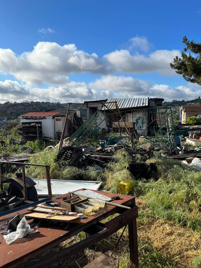 An overgrown yard filled with scrap metal, debris, and old structures, ready for Jake's Junk Removal in San Diego, CA.