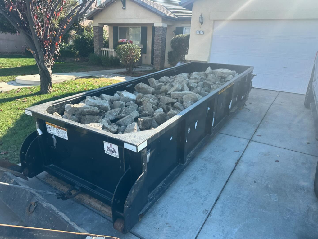 A residential roll-off dumpster filled with rocks and debris by Bakersfield Roll-Off Service in Bakersfield, CA.