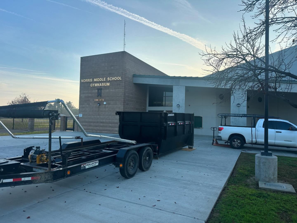 A roll-off dumpster and trailer provided by Bakersfield Roll-Off Service for a school project in Bakersfield, CA.