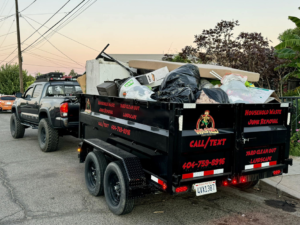 A Wasted Junk Removal truck pulling a trailer overflowing with household junk and debris in Fresno, CA.