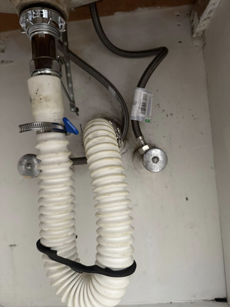 Under-sink plumbing with P-trap and supply lines installed by Peraza Handyman Services Llc in Bakersfield, CA.