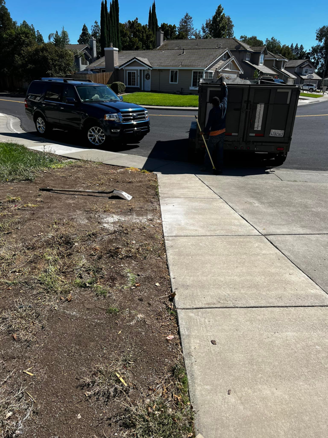 A worker standing by a junk removal trailer with a shovel on the ground, ready for a job by We Haul It All in Lakeland, FL